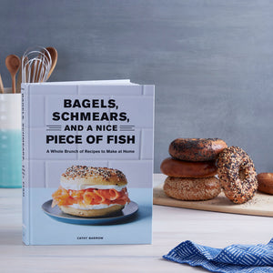 Bagels, Schmears and a Nice Piece of Fish on a kitchen counter with utensils, a stack of bagels and a dish towel