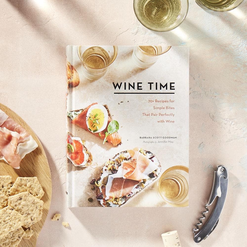 Wine Time on tabletop with corkscrew, two glasses of sparkling white wine and charcuterie board